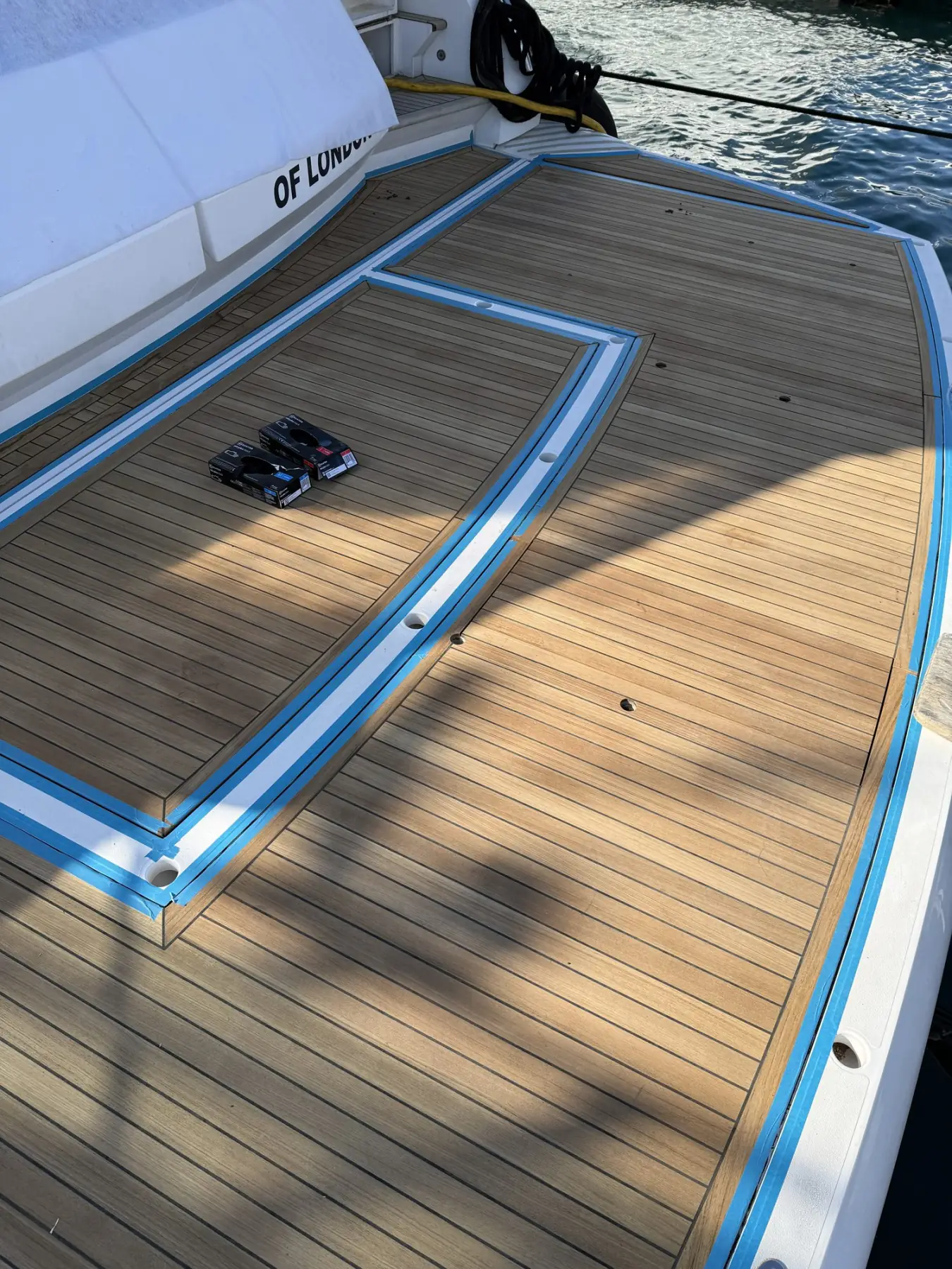 Foredeck being sanded, margins masked with blue tape